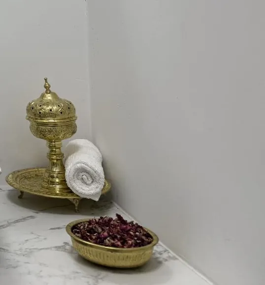 A brass burner, a rolled towel and dried rose petals