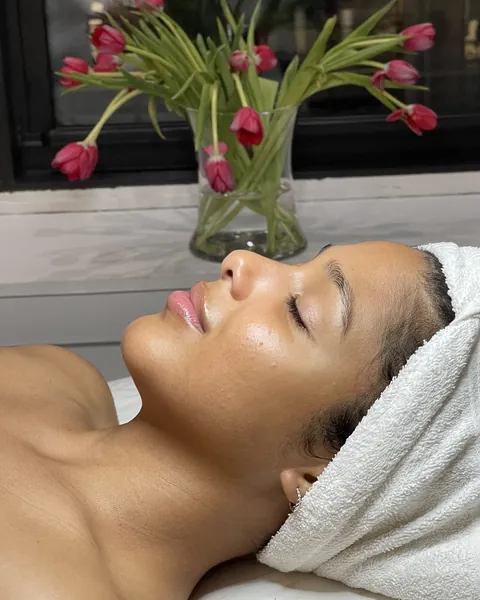 A client resting on the treatment bed, hair wrapped in a towel, tulips by the window